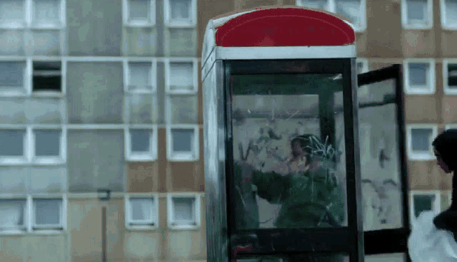 a phone booth with graffiti on it and a man standing outside