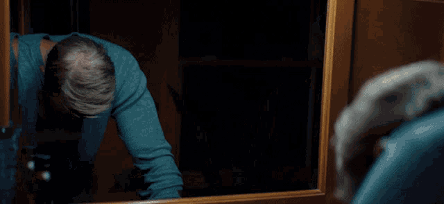 a man is looking at himself in the mirror in a dark room