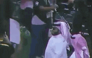 a man in a white robe is kneeling down in front of a crowd .