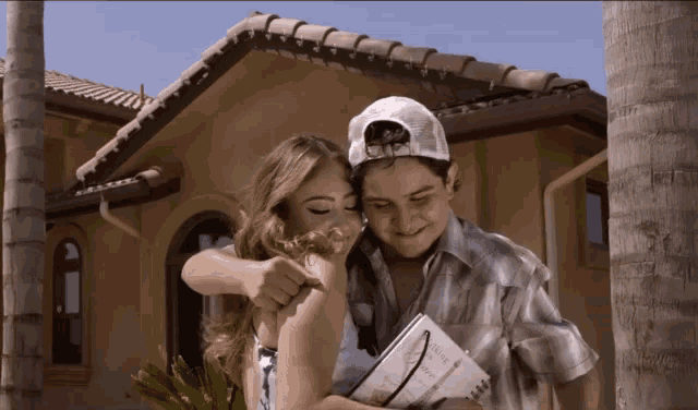 a man and a woman are hugging in front of a building