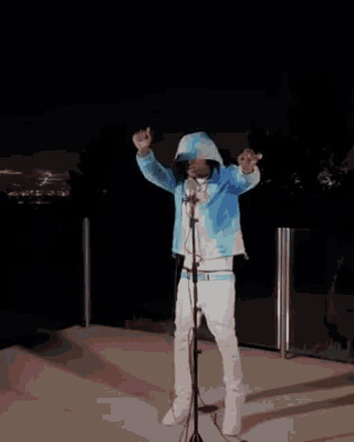 a man in a blue jacket is standing in front of a microphone .