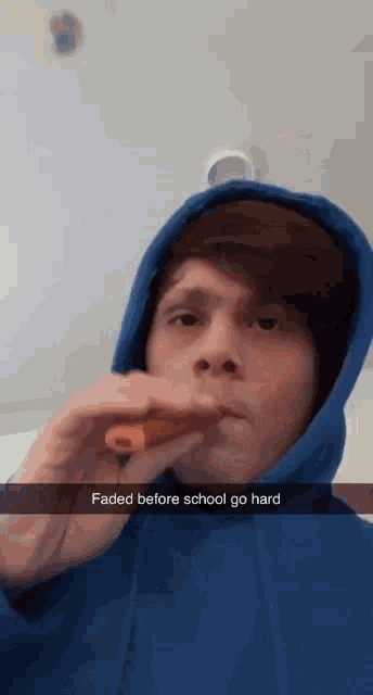 a man in a blue hoodie smoking an electronic cigarette