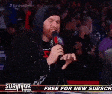a man is speaking into a microphone in front of a sign that says free for new subscribers