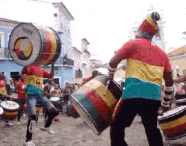 a group of people are playing drums in a parade in a city .