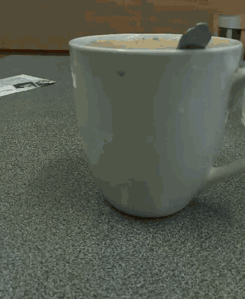 a cup of coffee is sitting on a table next to an envelope with a picture of a man on it