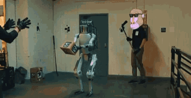 a robot is carrying a box and a man is standing next to it with a hockey stick .