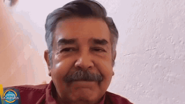 a man with a mustache is smiling in front of a sign that says la alegria