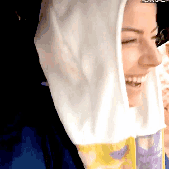 a woman wearing a hooded sweatshirt is smiling and holding a bag of chips