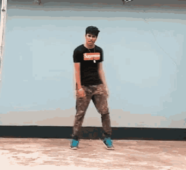 a young man wearing a supreme t-shirt is dancing