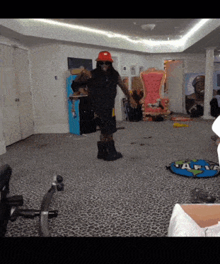 a man wearing a red hat and sunglasses is dancing in a room with a chair and a leopard print carpet
