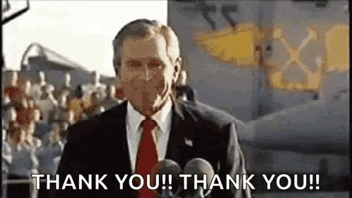 a man in a suit and tie is standing in front of two microphones and saying thank you .