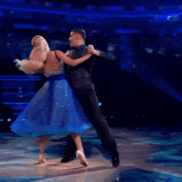 a woman in a blue dress dancing with a man