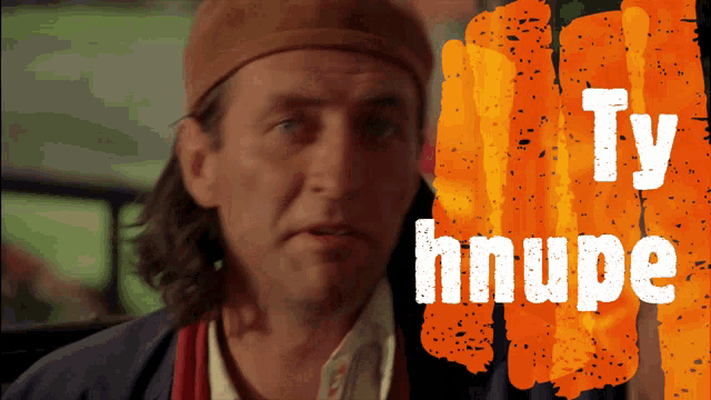 a man wearing a hat is standing in front of an orange background that says ty hnupe