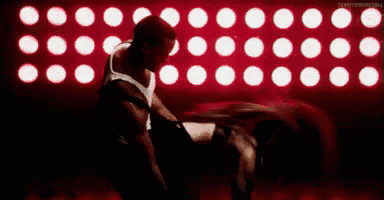 a man and a woman are dancing in front of a wall of red lights .