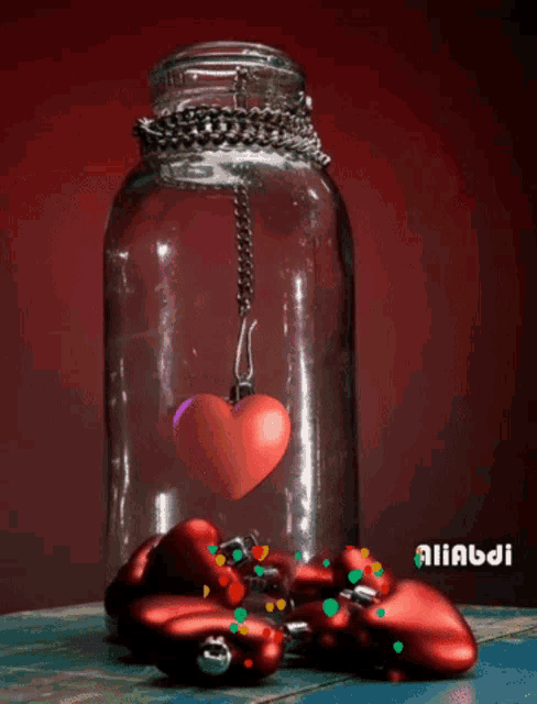 a glass jar with a red heart hanging from it and the name alibabi on the bottom