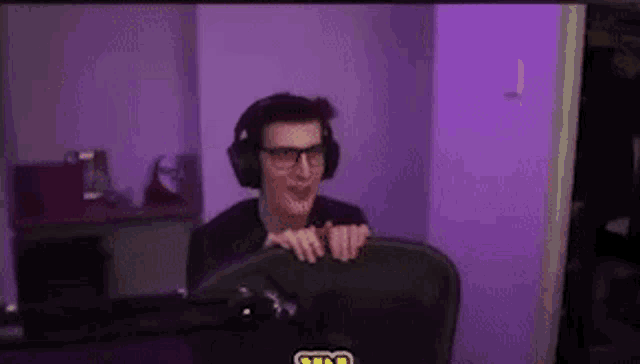 a man wearing headphones is sitting in front of a computer screen .