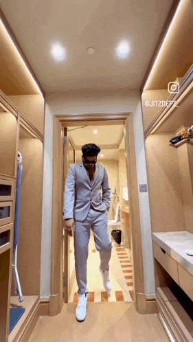 a man in a suit is standing in a walk in closet ..