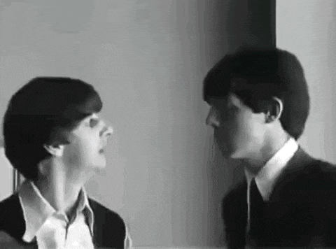 a black and white photo of two men standing next to each other and looking at each other .
