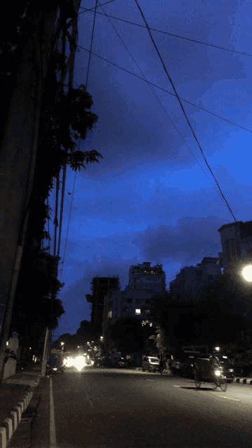 a dark street with a blue sky and a few buildings in the background