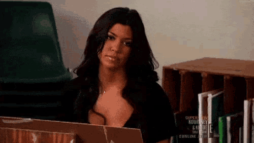 a woman is sitting in a library with a laptop .