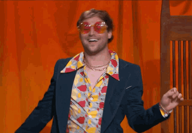 a man wearing a colorful shirt and sunglasses is smiling