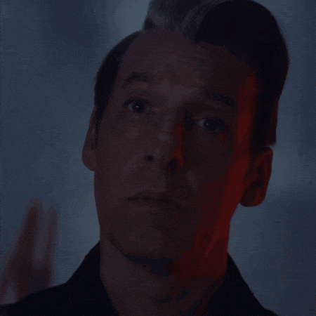 a close up of a man 's face with a red light behind it