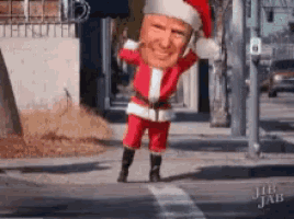 a man in a santa suit is walking down a street .