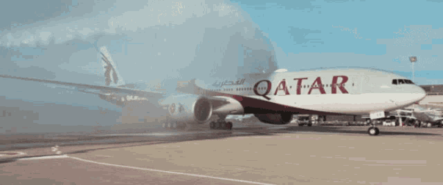 a red and white qatar airplane is parked on the runway