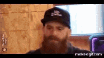 a man with a beard is wearing a black hat with the word mc on it .