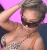 a woman wearing sunglasses and a bra is holding her hair .