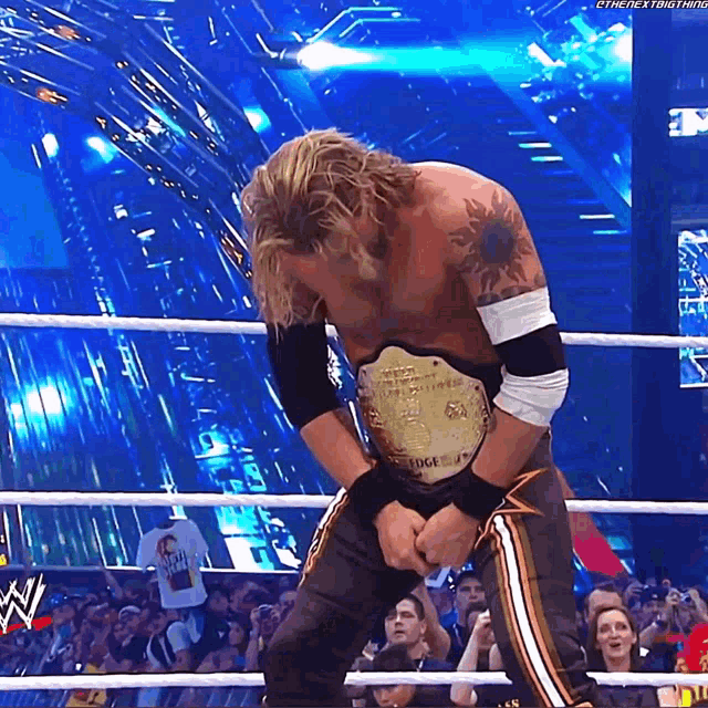 a man in a wrestling ring is wearing a gold belt that says ' the next thing ' on it