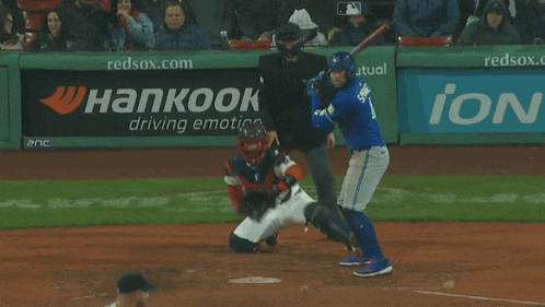 a baseball player swings at a pitch in front of a banner for hankook driving emotion