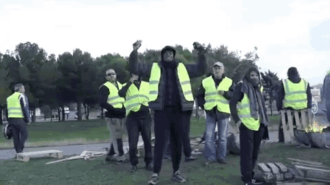a group of men wearing yellow vests are standing in a field .