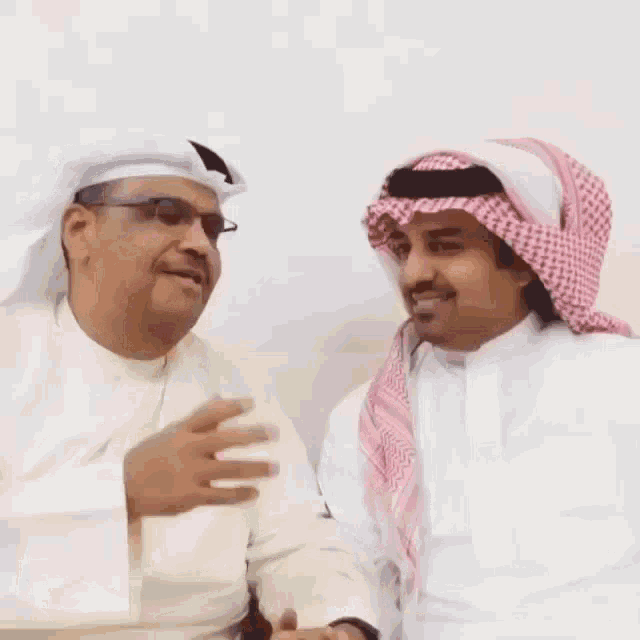 a man in a white shirt is talking to another man