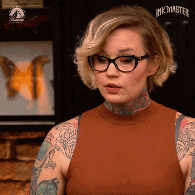 a woman wearing glasses stands in front of a paramount sign that says ink master