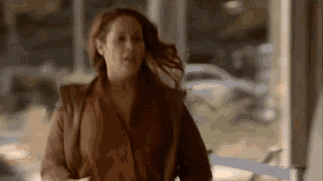 a woman in a brown jacket and red blouse is running