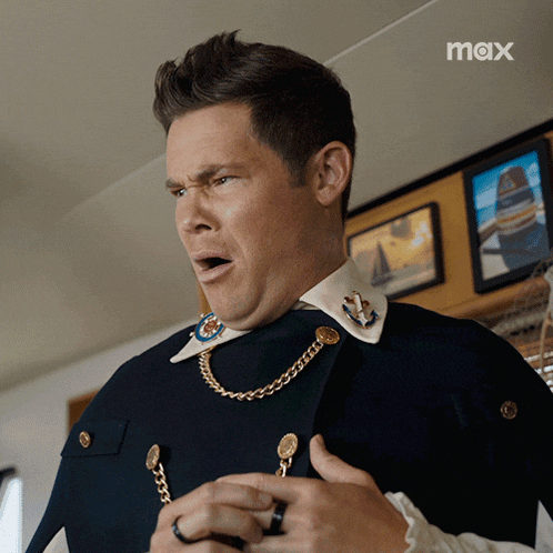 a man is wearing a cape and a necklace with the word max on the bottom right