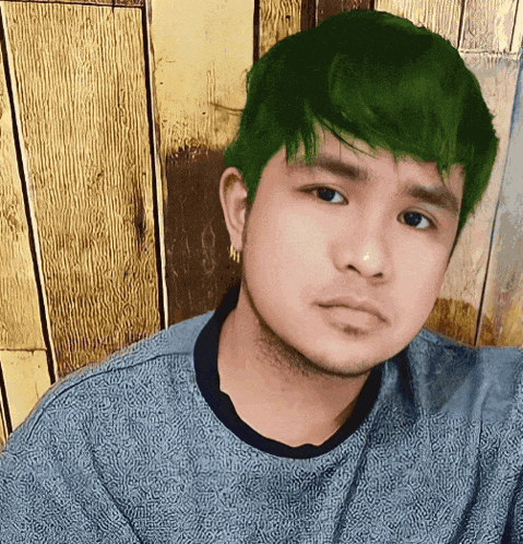 a young man with green hair is wearing a blue sweater
