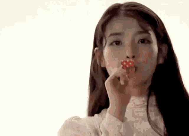 a woman is holding a heart shaped lollipop in her hand .