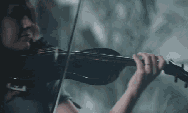 a woman is playing a violin with a blurred background