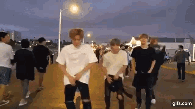 a group of young men are standing on a sidewalk dancing .