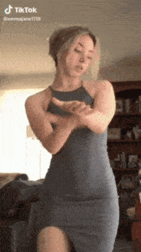 a woman in a gray dress is standing in a living room .