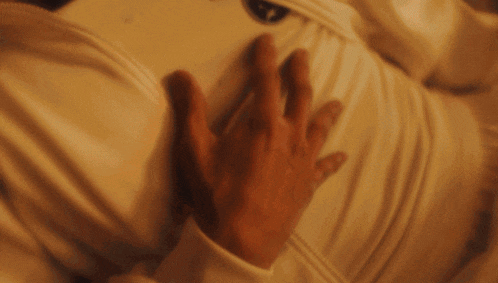a blurry picture of a person 's hand touching another person 's shirt that has the letter r on it