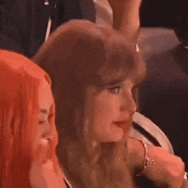 two women are sitting next to each other in a crowd .