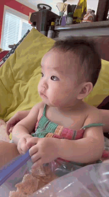 a baby in a colorful dress is sitting on a bed