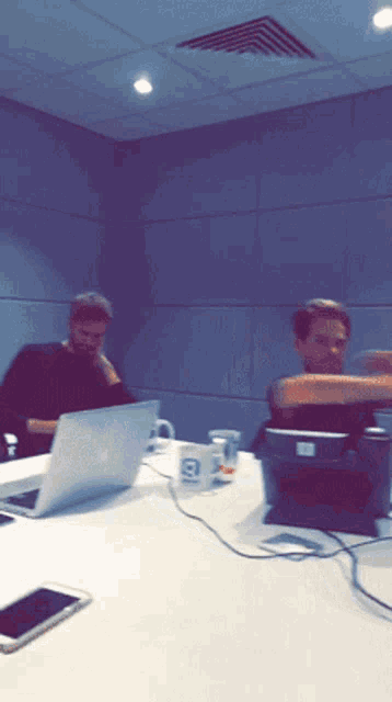 a man sits at a table with a laptop and a mug that says ' b ' on it