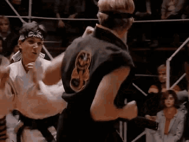 two karate fighters are fighting each other in a ring .