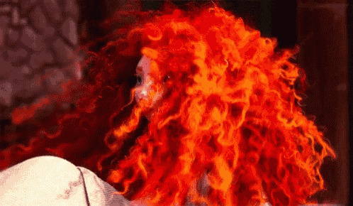 a close up of a woman 's red hair that looks like fire .