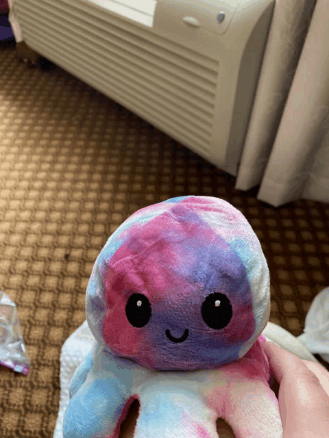 a person is holding a stuffed octopus that is pink and purple
