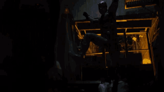 a man in a boxing glove is standing next to another man in a dark room .